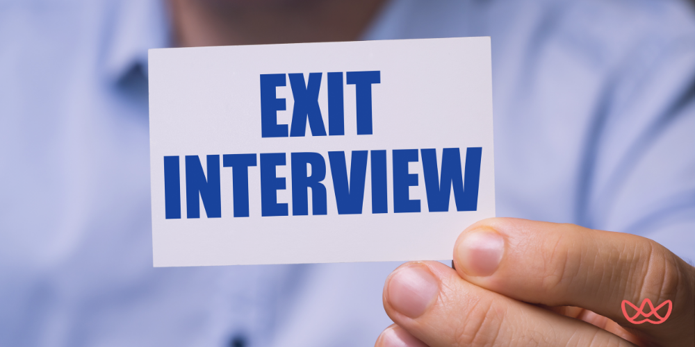Person holding a card that reads EXIT INTERVIEW, symbolizing the final meeting in the employment termination process.