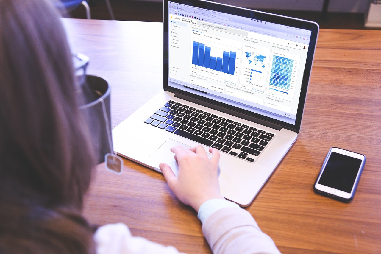Close-up of a person working on a laptop with graphs and charts on the screen, suggesting data analysis or business work.