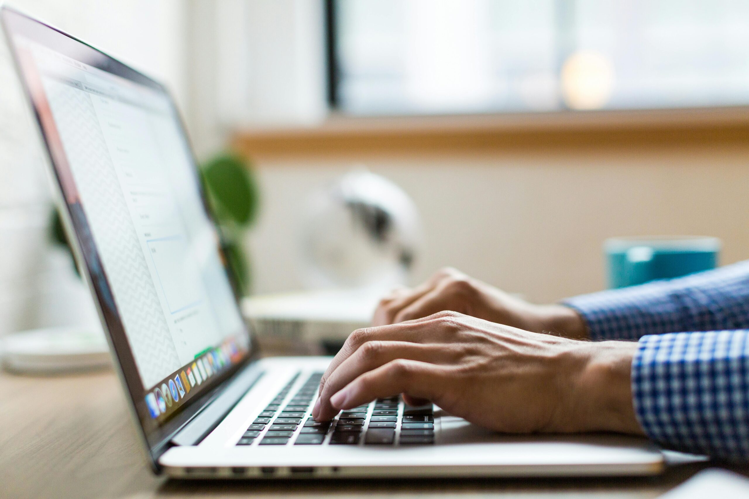 A close-up image of a person’s hands typing on a laptop keyboard with the screen displaying an email, possibly related to the termination of employment email.