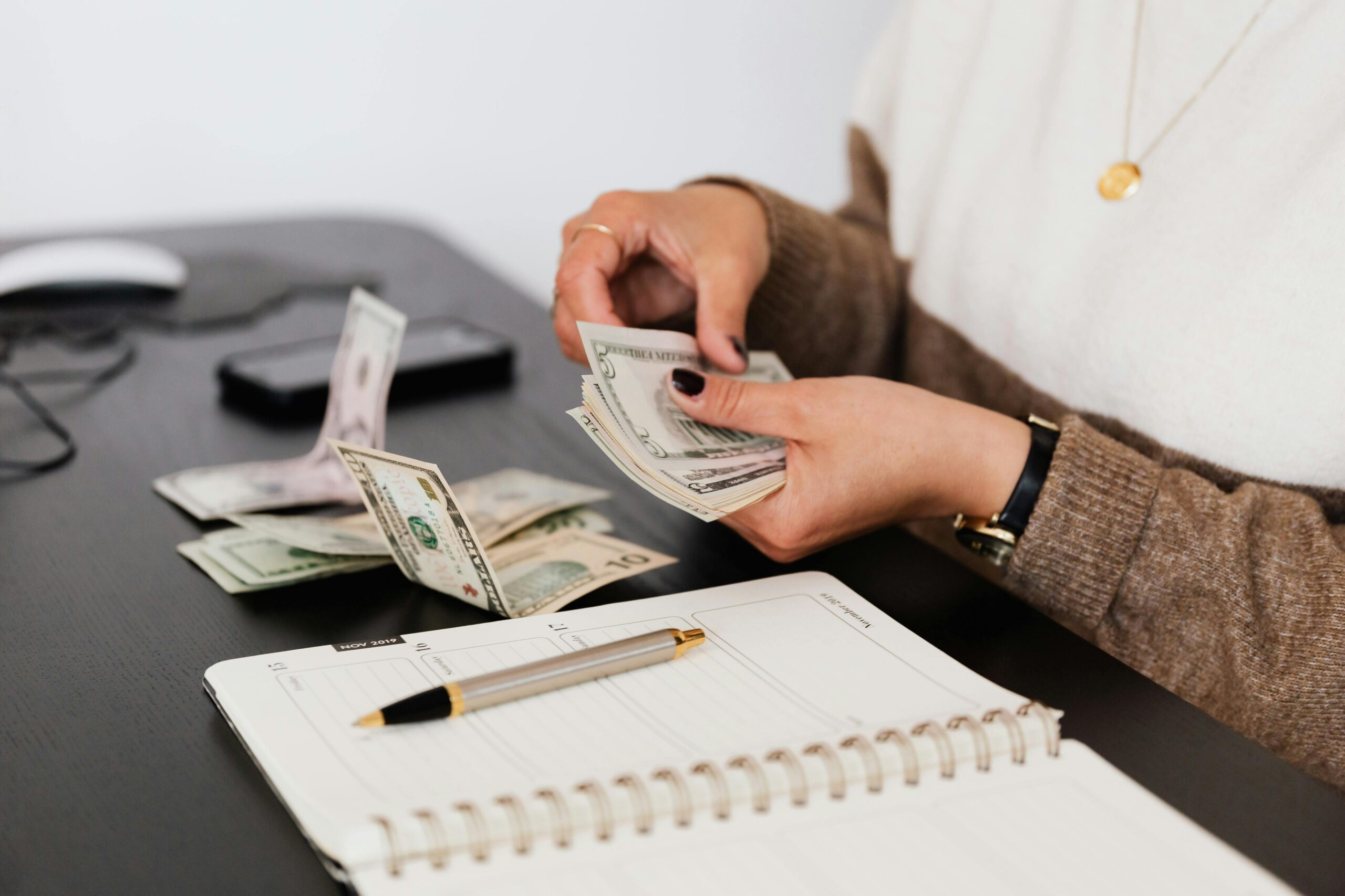 A person counting money, a practical task related to interview questions for a bookkeeper.