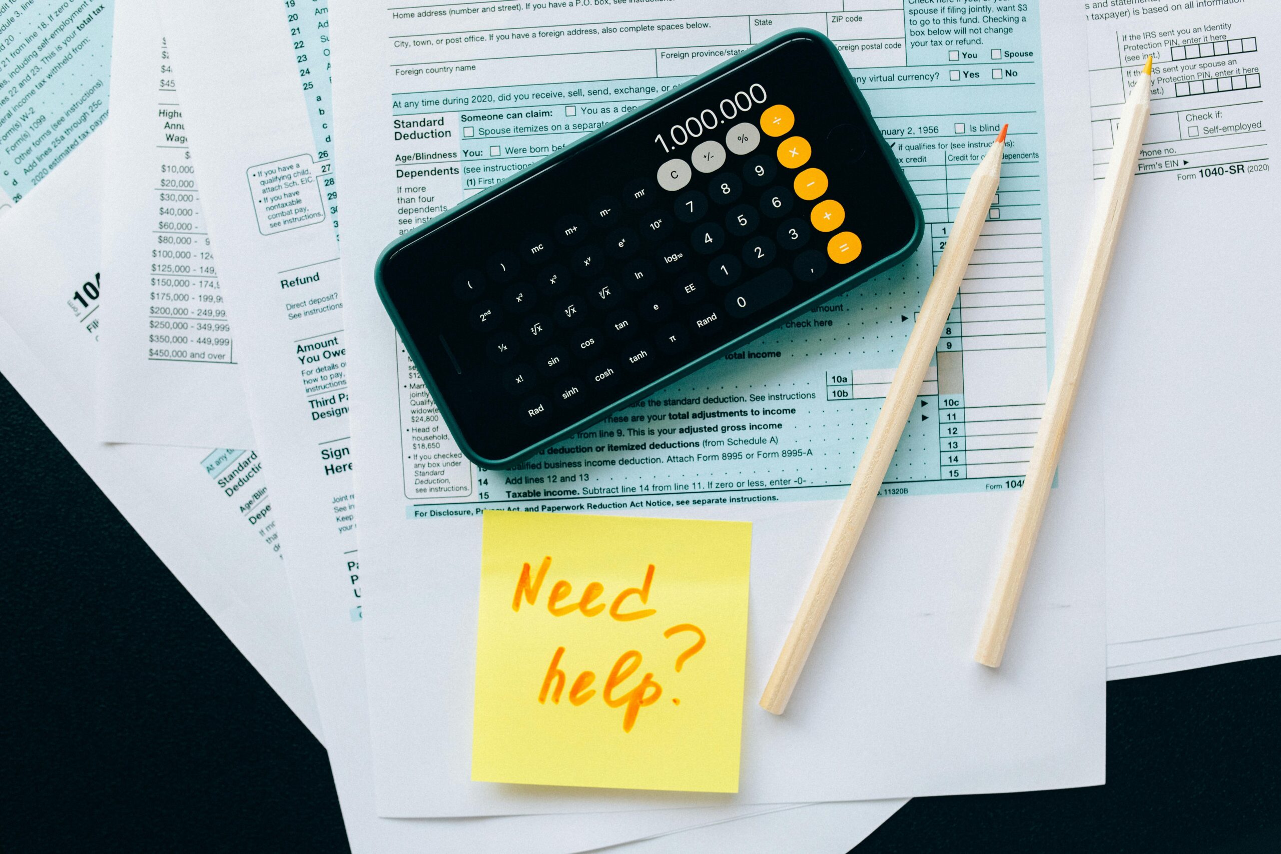 A phone calculator displaying a large number on top of tax documents, illustrating the help of accounting services outsourcing.
