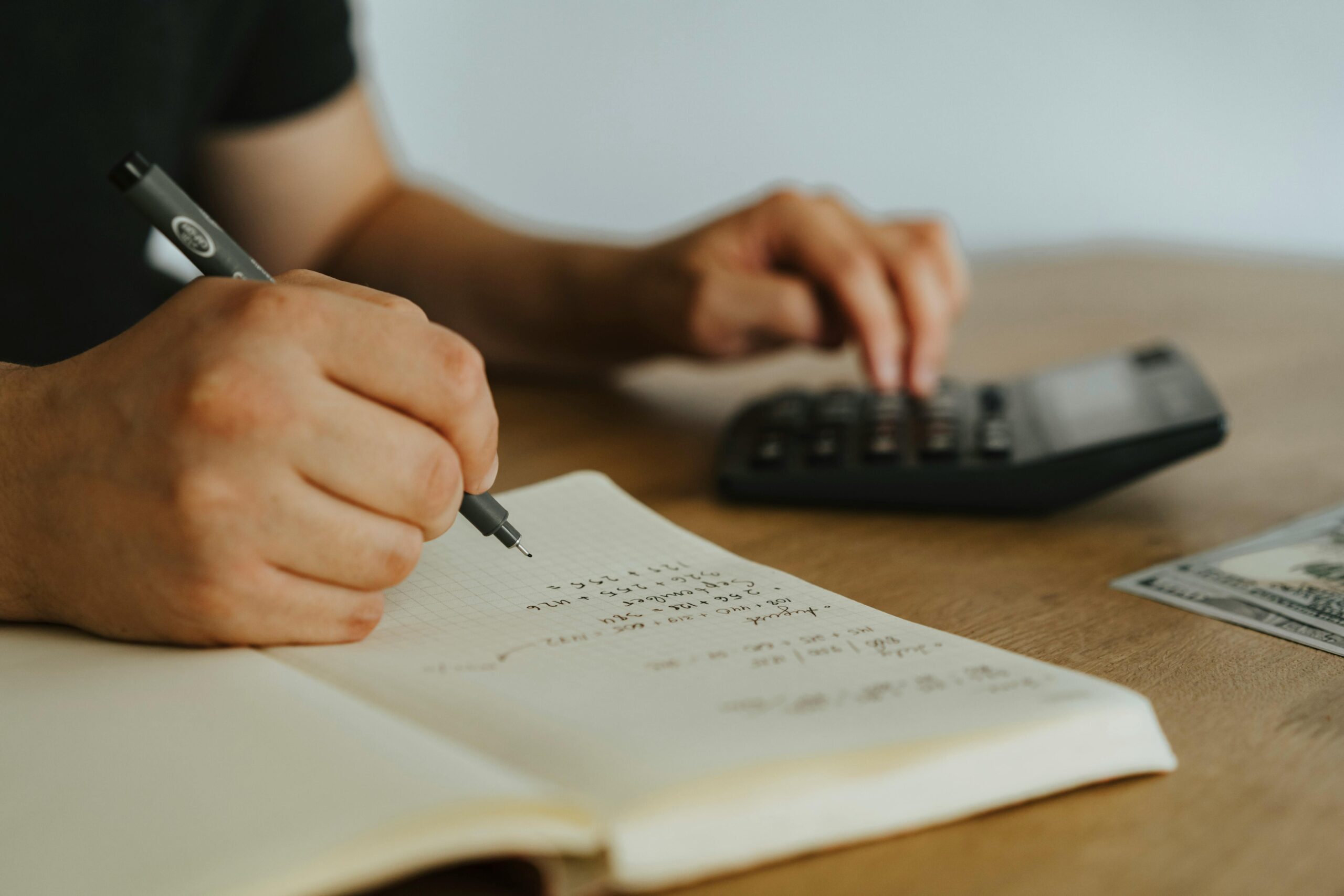 A person calculating finances with a notebook and calculator.
