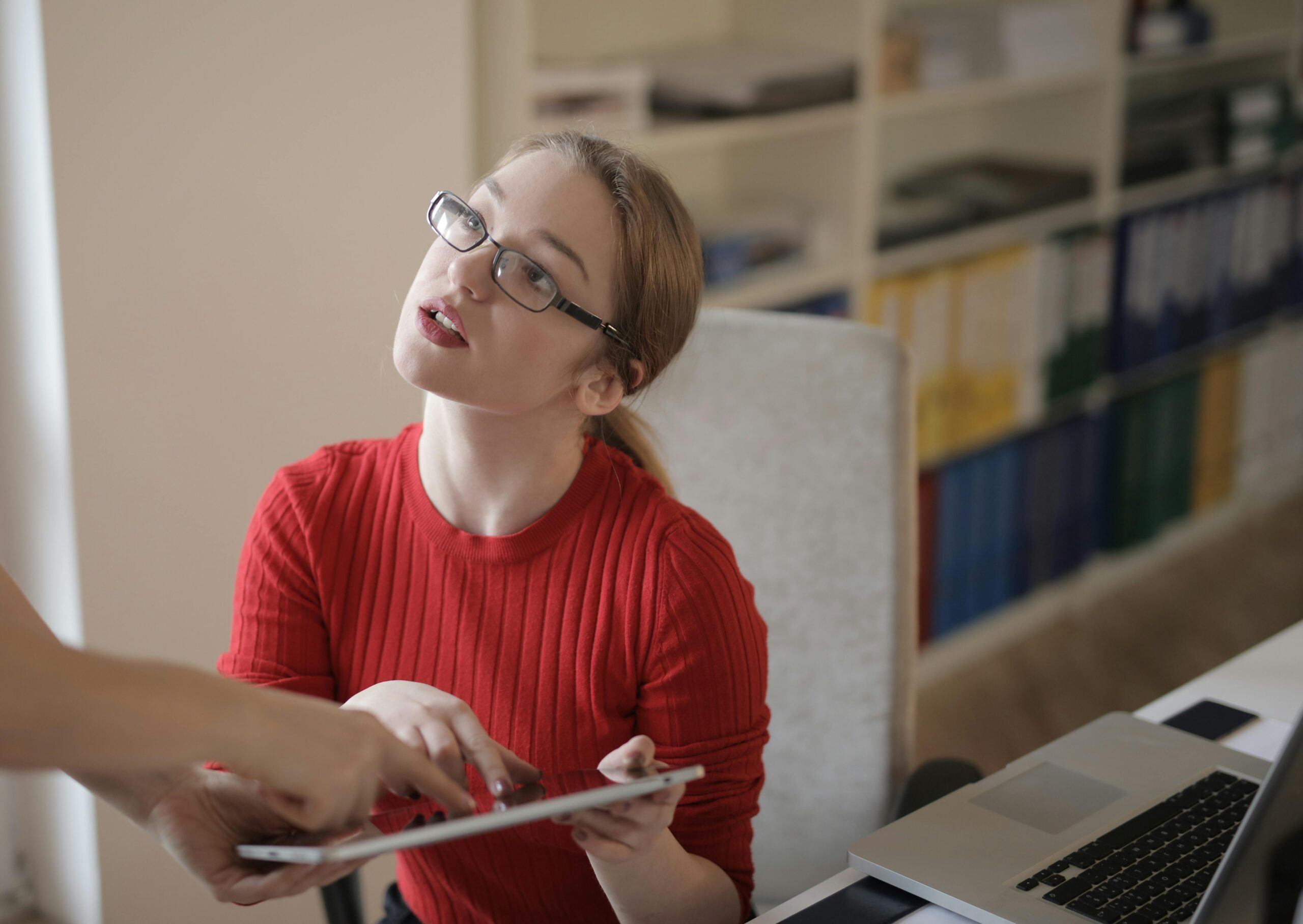 A professional with a tablet and laptop, likely reviewing interview questions for a bookkeeper.