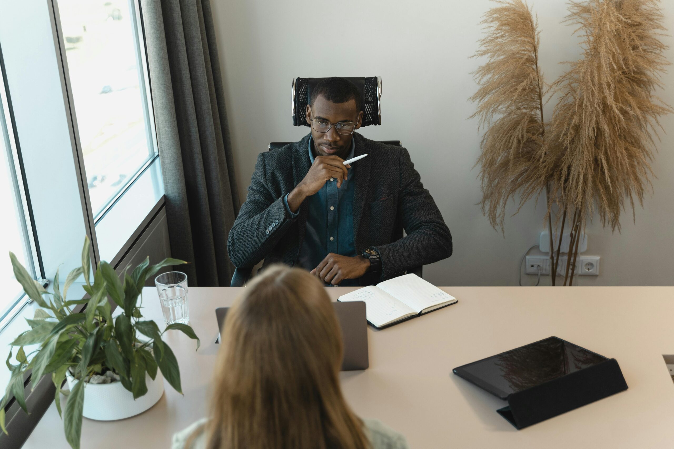 Talent hiring process visualized with a digital device replacing a person’s head at a meeting table.
