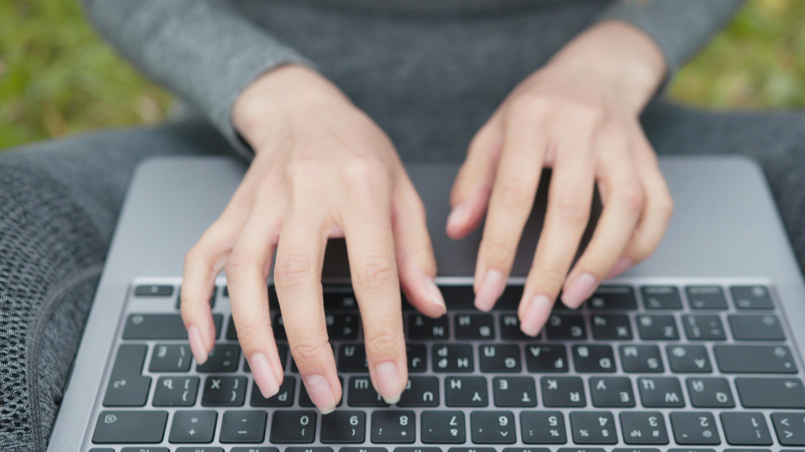 Close-up of hands typing on a laptop keyboard.