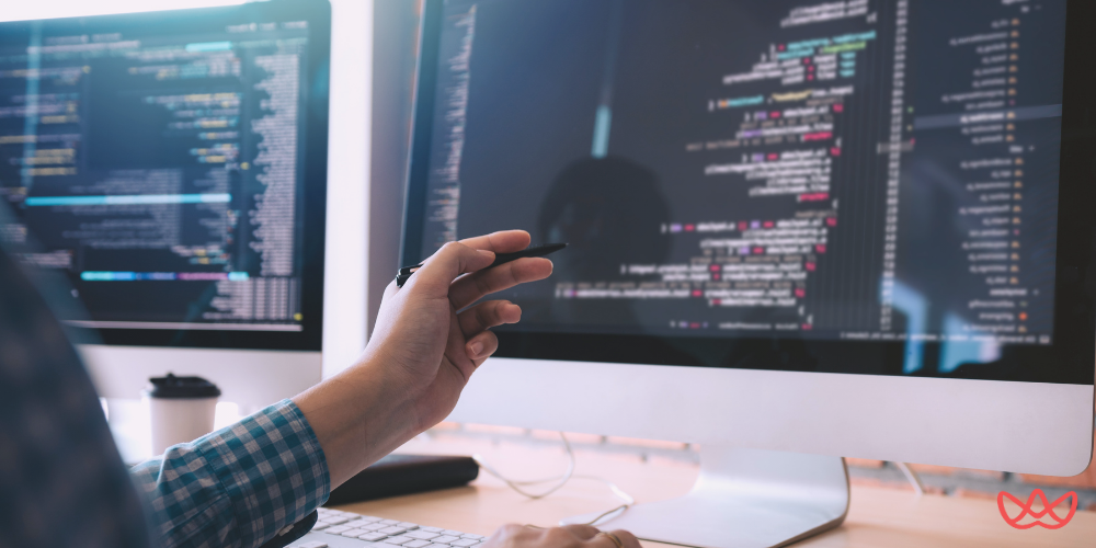 A software developer working on a dual-monitor setup with coding displayed on the screens, showcasing the expertise of hire LATAM developers.