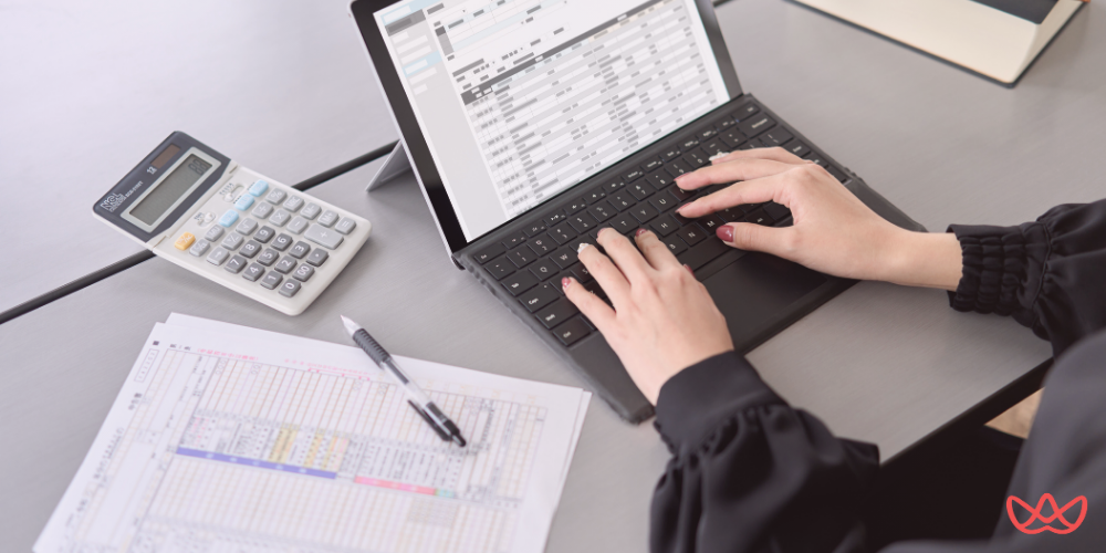 A professional working on a spreadsheet using a laptop and calculator, demonstrating outsource data entry efficiency.