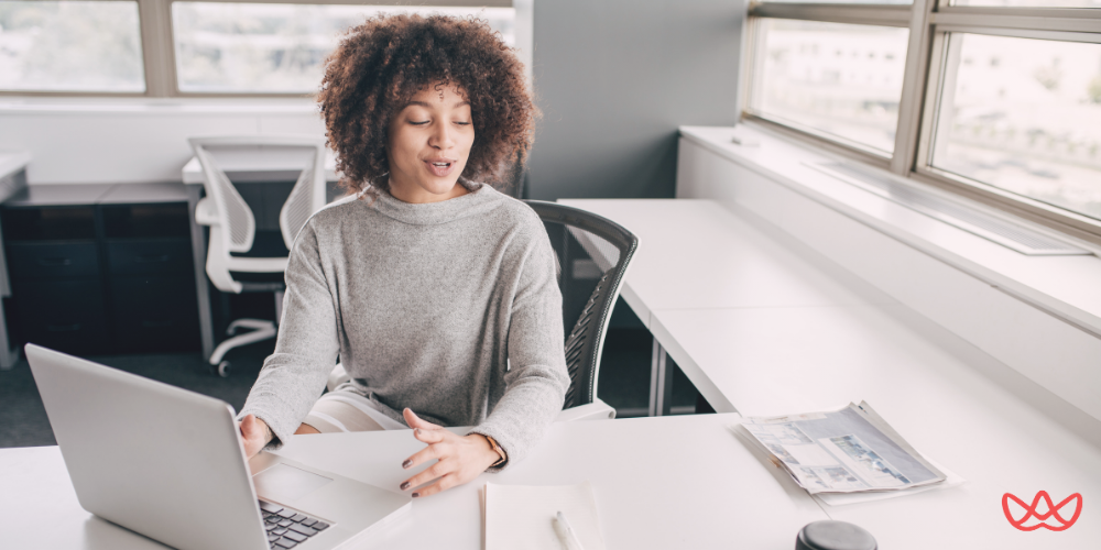 A professional woman working on a laptop in a bright office, representing the efficiency of a property management virtual assistant in managing real estate tasks.