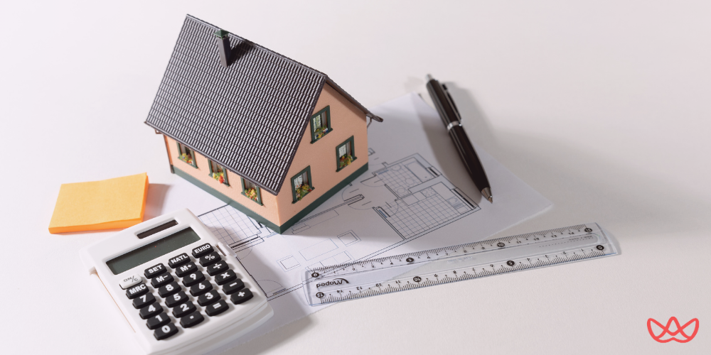 A miniature house model on architectural plans with a calculator and pen, symbolizing real estate virtual assistance in project planning and management.