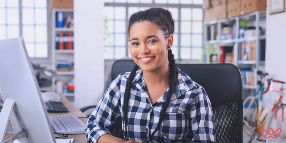 A smiling professional working at her desk, embodying the efficiency of a social media virtual assistant.