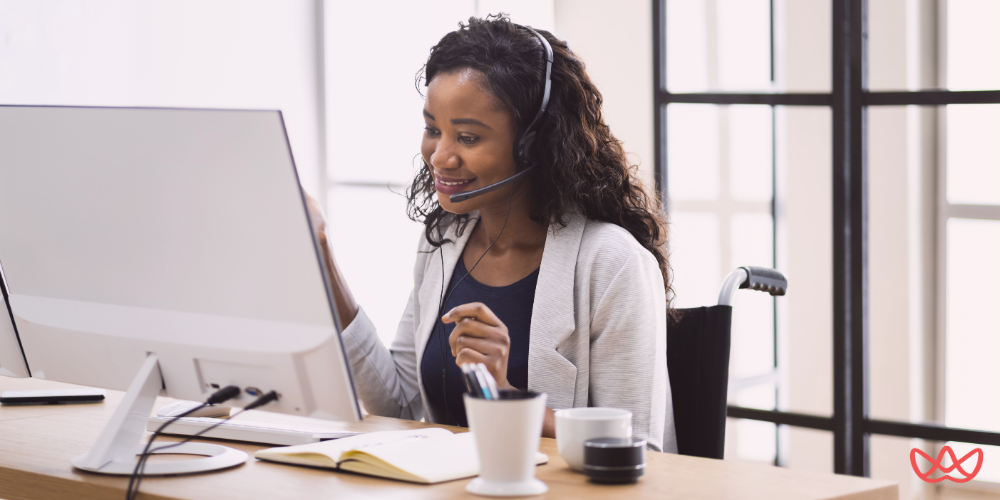 A smiling professional woman wearing a headset while working on a computer, representing the benefits of a virtual assistant in customer support.