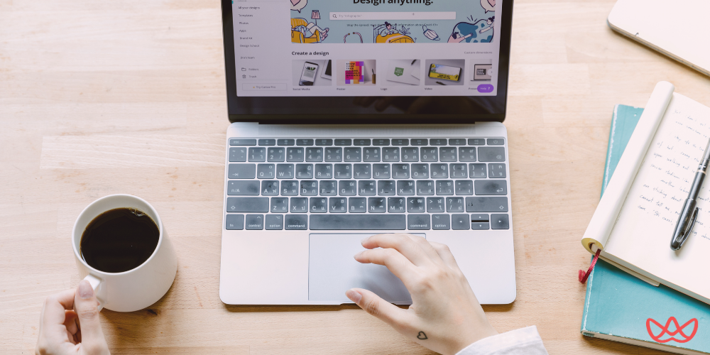 Close-up of a person using a laptop with coffee and notebooks, showcasing virtual assistant tools for productivity.