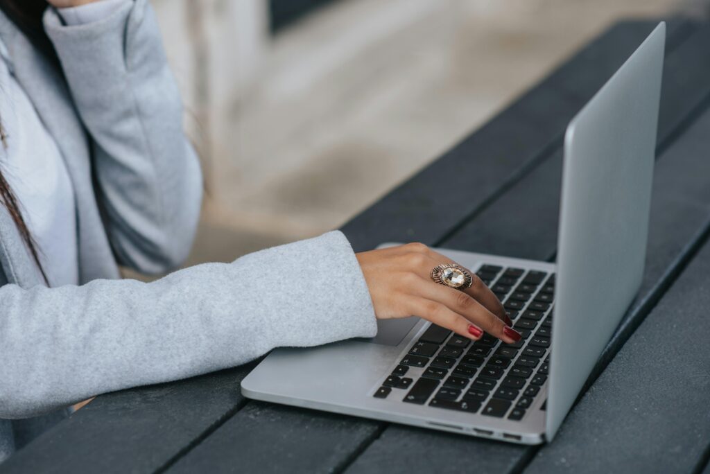 A close-up of a professional typing on a laptop outdoors, reflecting the flexibility of outsourced sales & marketing tasks.