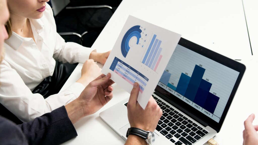 A team reviewing campaign performance data on a laptop and charts, highlighting the strategic planning offered by campaign managers for hire to achieve business goals.
