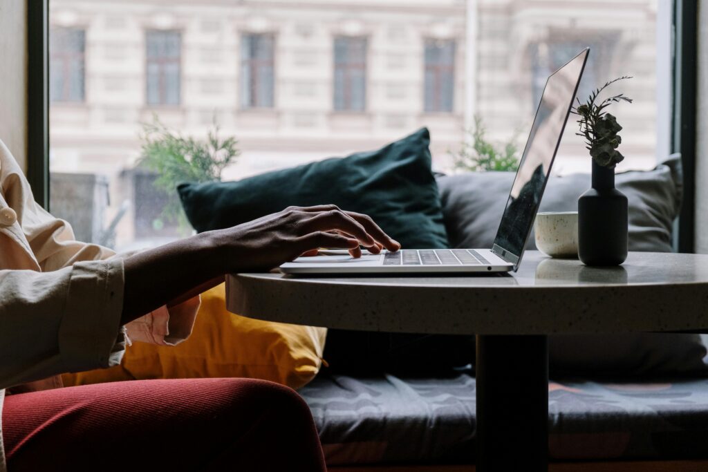 A person working on a laptop in a cozy setting, representing the remote flexibility offered by examples of outsourcing companies.