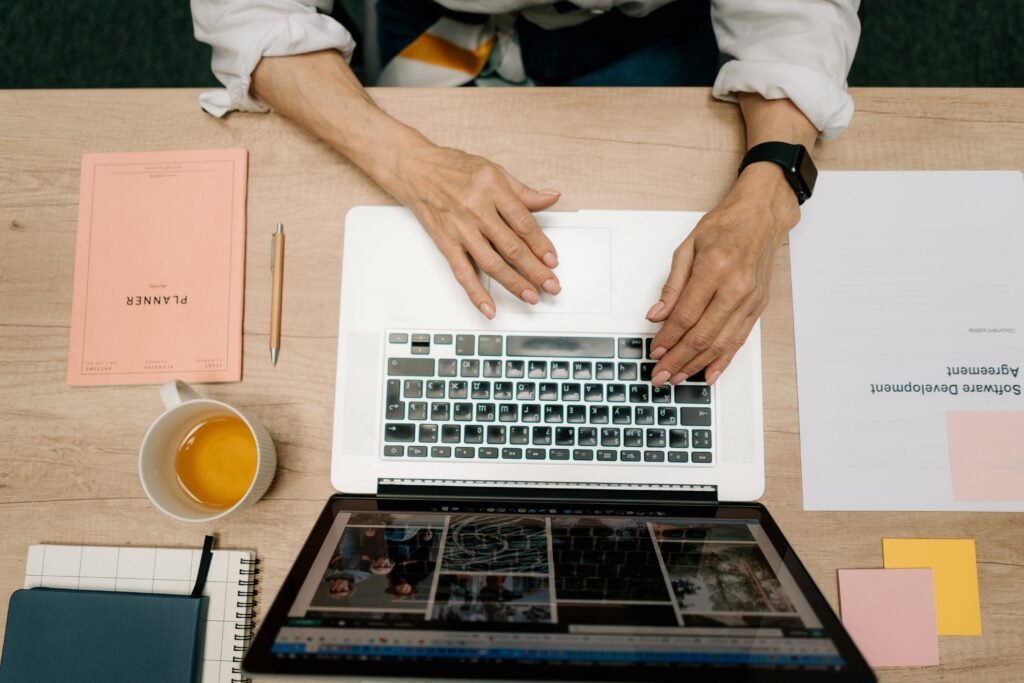 Overhead shot of a person working on a laptop with organized documents, showcasing a freelance business assistant for small and medium businesses.