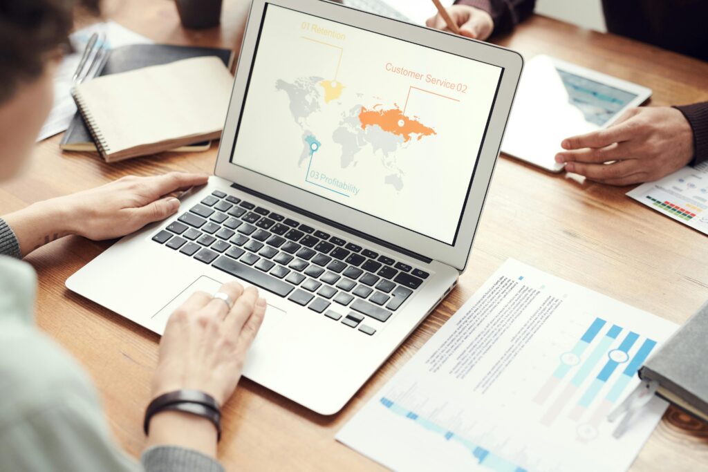 A laptop displaying a world map with campaign metrics, surrounded by marketing documents, showcasing the global reach facilitated by campaign managers for hire.