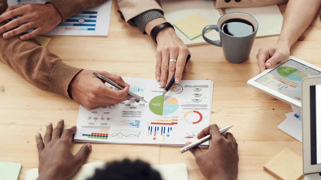 A collaborative team reviewing marketing reports and charts during a meeting, underscoring the collaborative efforts a marketing hire contributes to business growth.