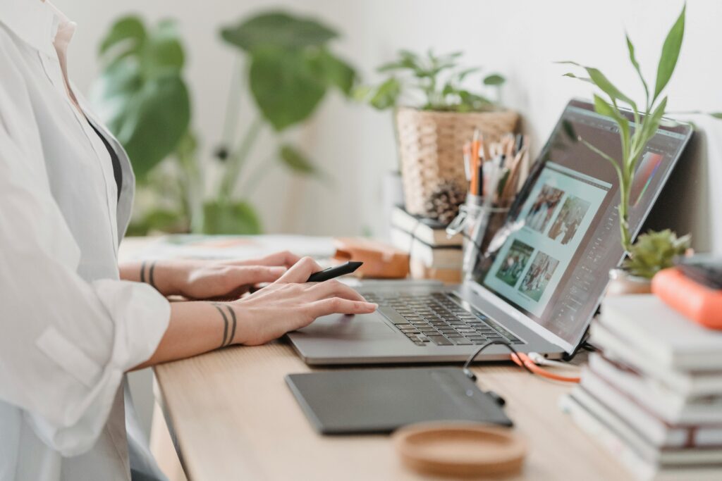 Designer working on a laptop with a digital drawing tablet, perfect for graphic artist hire projects.