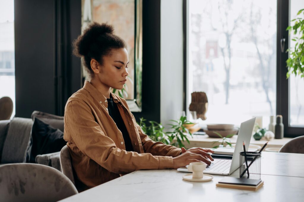 A focused woman working on her laptop at a stylish desk, showcasing the role of a short-term rental virtual assistant.