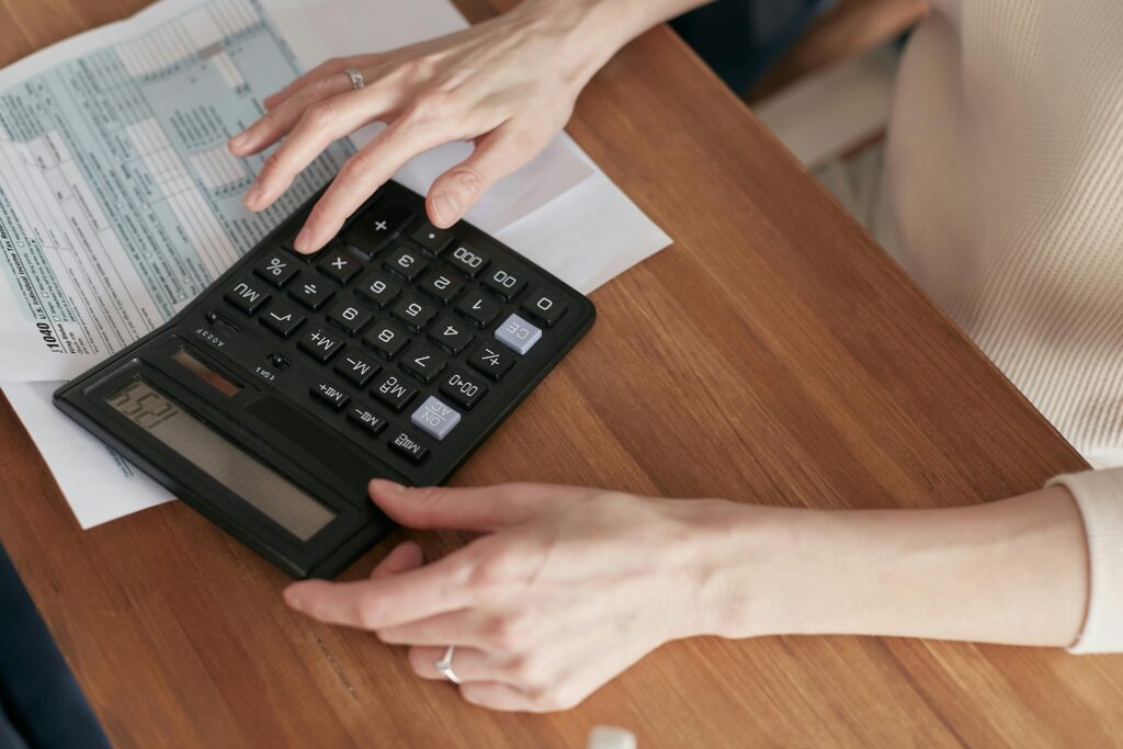Hands using a calculator on a wooden table, representing the analytical approach of hiring an SEO expert for measurable results.