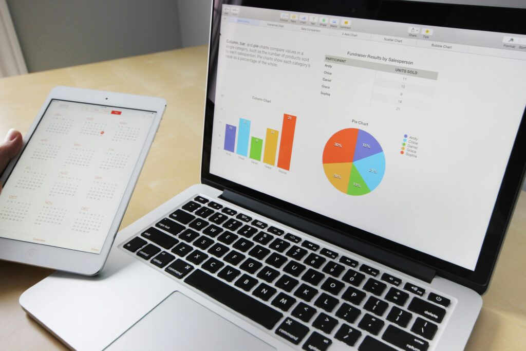 A laptop displaying charts and graphs alongside a tablet calendar, showcasing outsource data entry solutions for business insights.