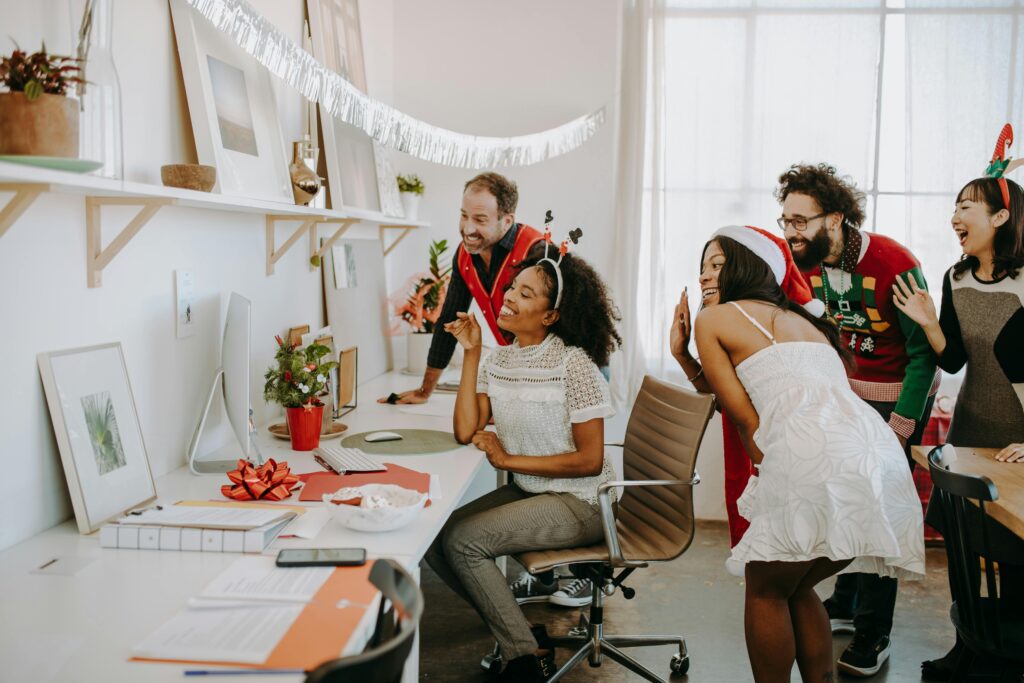 A cheerful team in a decorated office connecting with their outsourced marketing department during a festive video call.