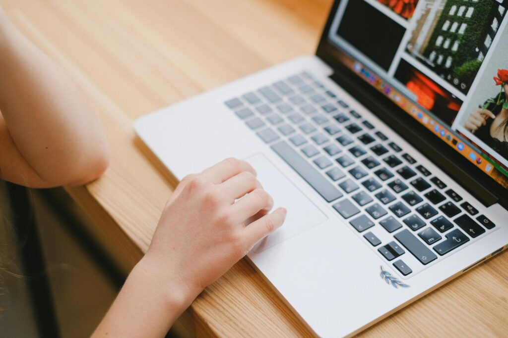 A close-up of a person's hand navigating on a laptop touchpad, symbolizing online research about "why do companies engage in outsourcing."