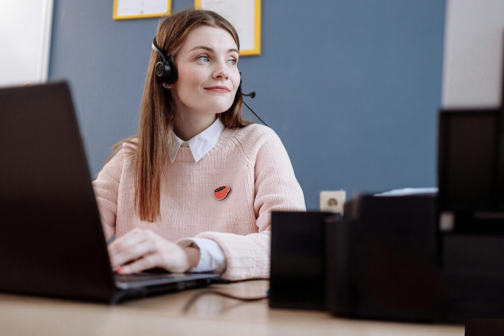 Help desk representative in a pink sweater, demonstrating the benefits of outsourcing help desk services for seamless customer interactions.