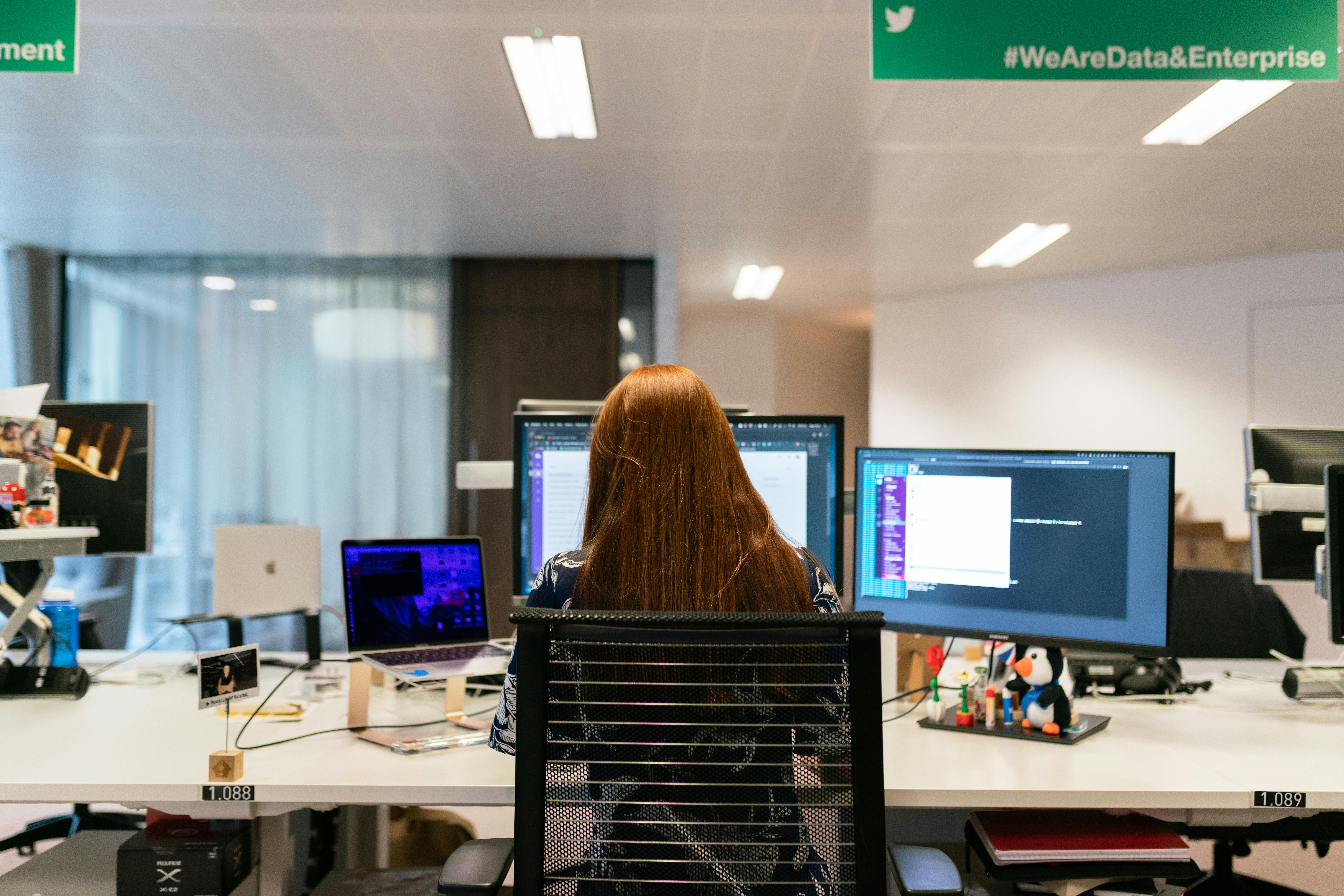 A professional working on multiple monitors in an office, highlighting advanced virtual assistant tools for multitasking.
