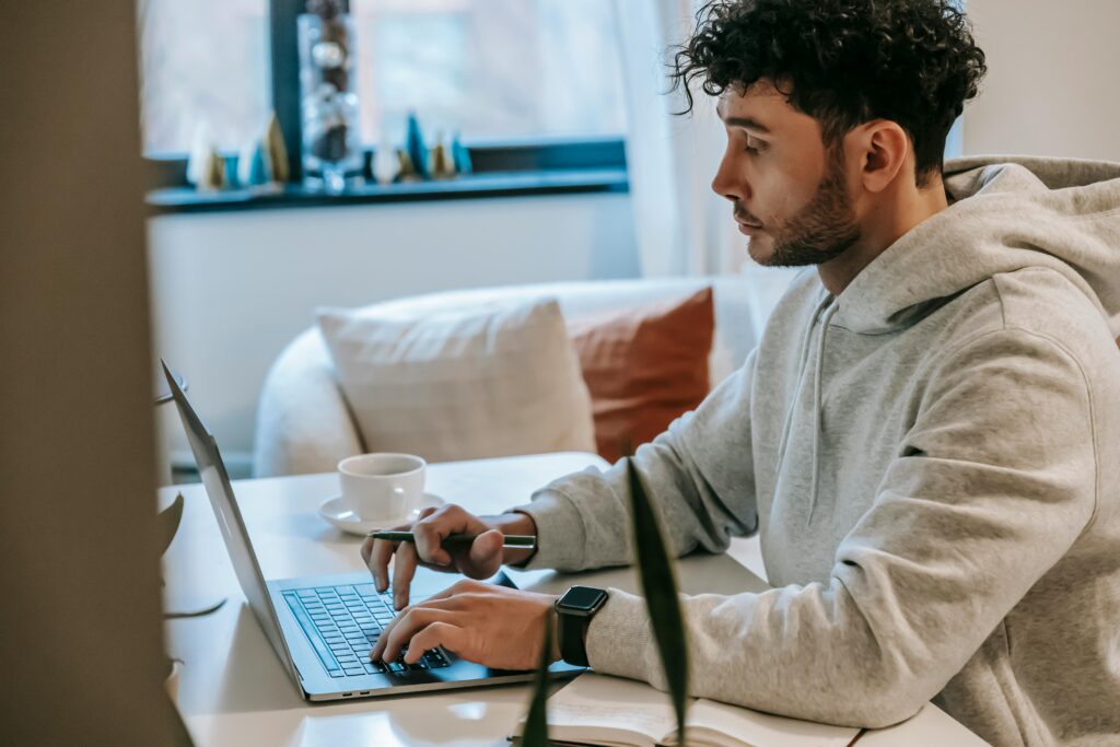 A remote worker at home typing on a laptop while discussing outsourcing staff for operational efficiency.