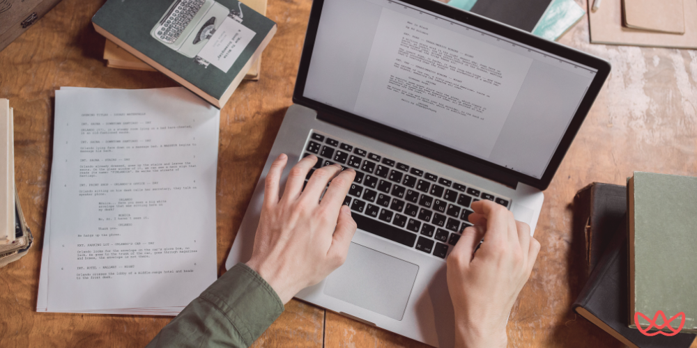 A person typing on a laptop with papers and books surrounding them, representing a copywriter key skills summary in action.