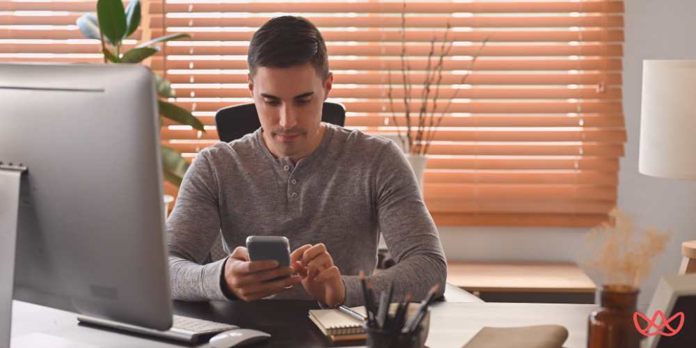 A marketing coordinator key skills summary is illustrated by a person sitting at a desk, using a smartphone, with a computer monitor, notebook, and office supplies in view.