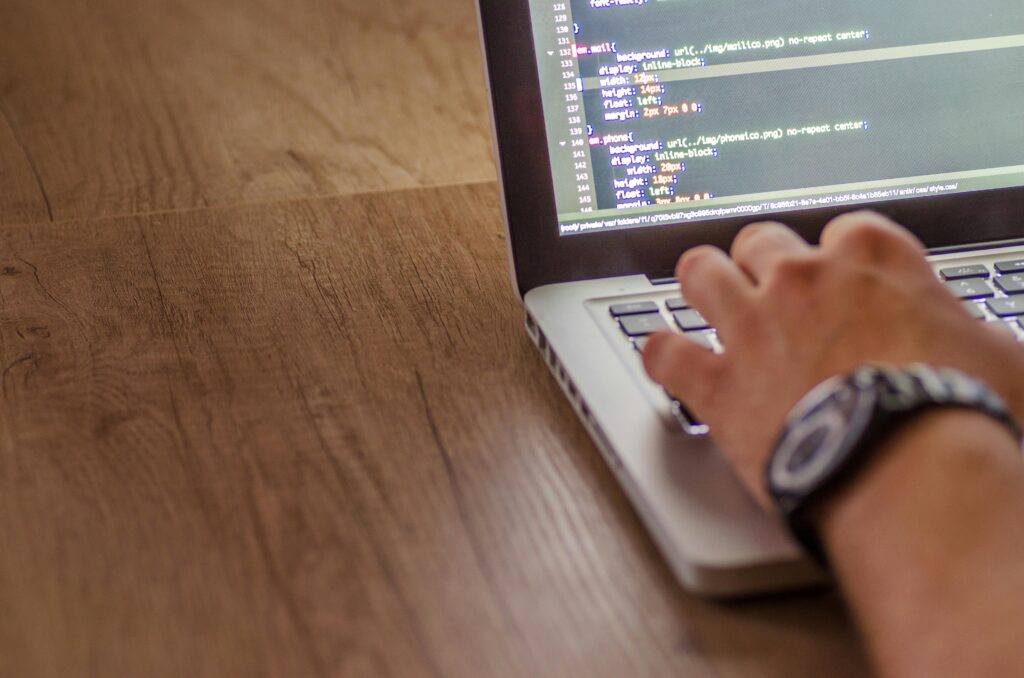 A frontend developer working on a laptop, coding in a text editor with HTML and CSS visible on the screen, showcasing key skills in web development.