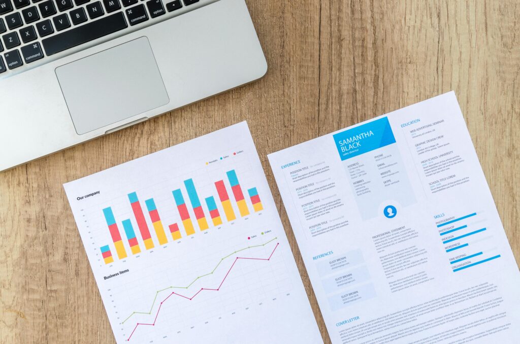 A modern resume featuring digital marketing consultant key skills summary alongside business performance graphs on a wooden desk with a laptop.