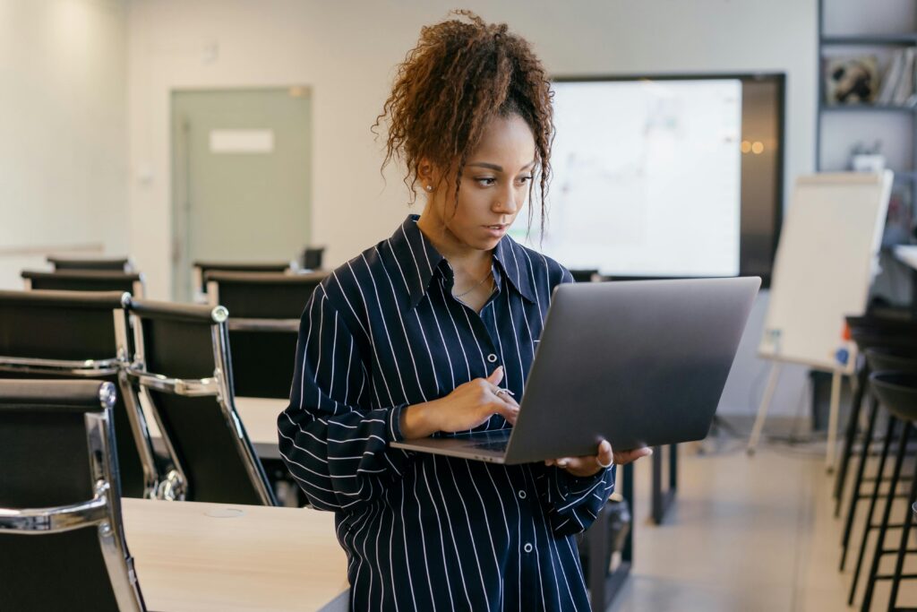 A person in a striped shirt working on a laptop in a modern office setting, illustrating the email marketing specialist key skills summary.