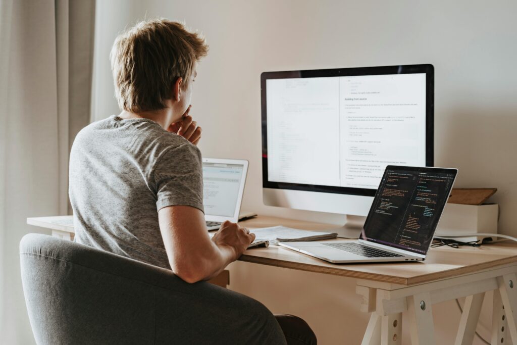 A full-stack developer working at a desk with multiple screens displaying code and documentation, summarizing key skills.