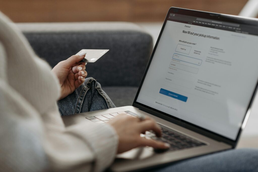 A person holding a credit card while entering information on a Shopify checkout page on a laptop, illustrating the importance of a Shopify CRO specialist key skills summary.