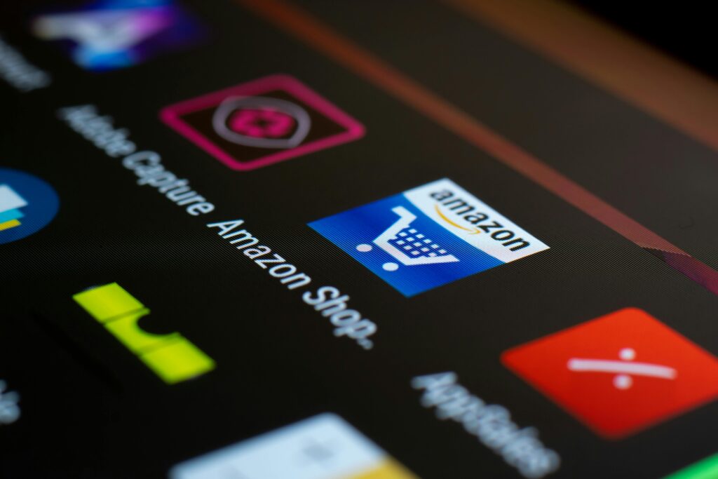 A close-up view of a smartphone screen displaying various app icons, including the Amazon Shopping app, which is relevant for understanding the key skills of an Amazon FBA consultant.