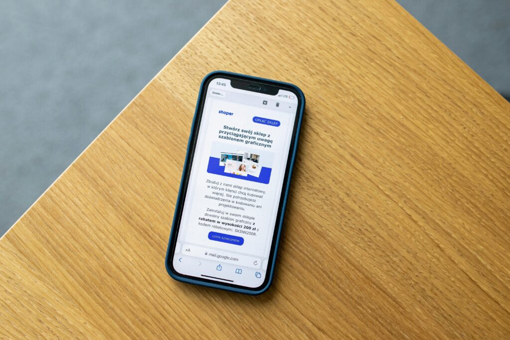 A smartphone with a blue case displaying an email on its screen, placed on a wooden table. The email appears to be a promotional message about creating an online store, relevant to the role of an Email Marketing Copywriter Key Skills Summary.