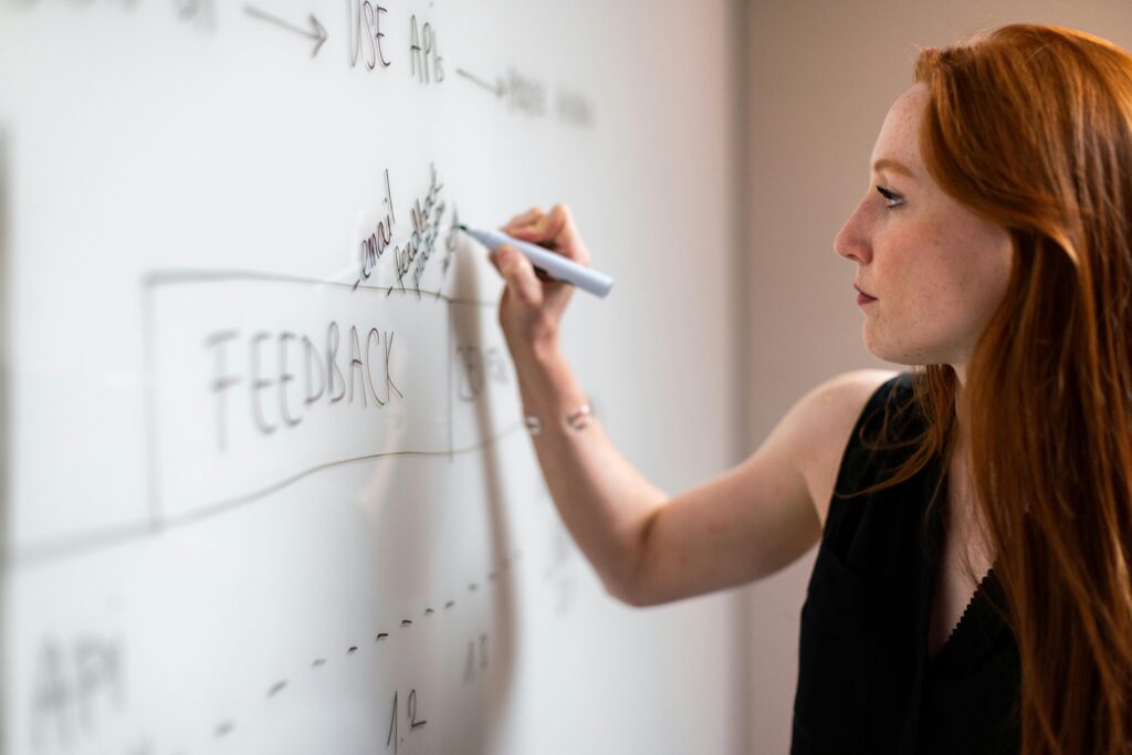 Agile project manager key skills summary: A person writing on a whiteboard with various project management terms and diagrams.