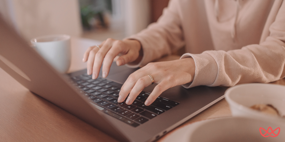 Hands typing on a laptop, with a coffee cup nearby, representing the HubSpot Consultant Key Skills Summary.