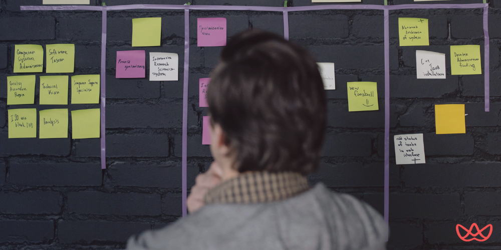 A product manager analyzing a task board with sticky notes, planning and strategizing for product development.