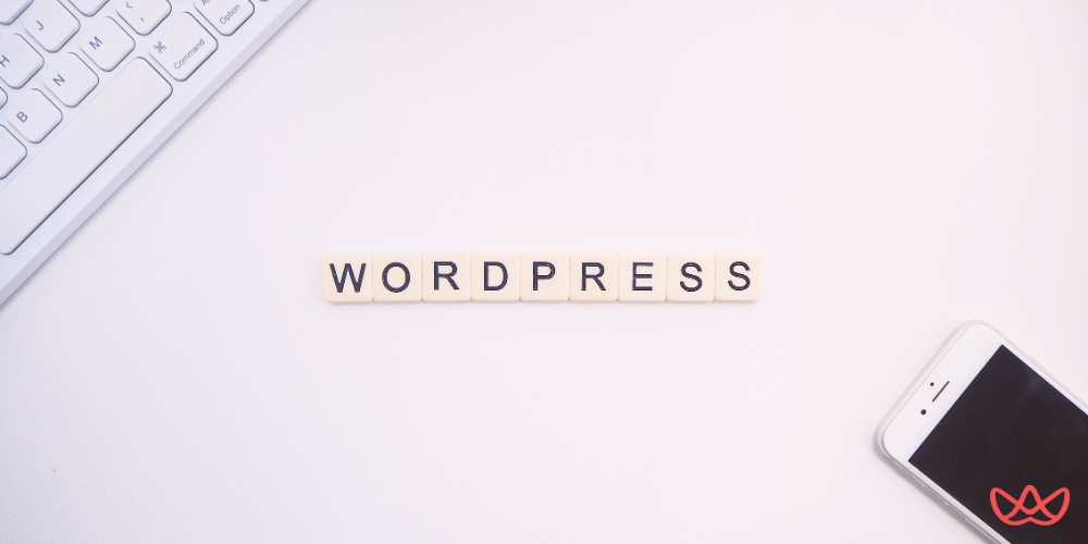 Scrabble tiles spelling “WORDPRESS” alongside a keyboard and smartphone, representing a WordPress developer key skills summary.