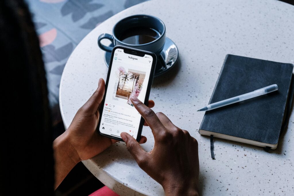 A smartphone displaying an Instagram post with palm trees and a beach scene, placed on a round table with coffee and a notebook, highlighting the Instagram Reels & Shorts specialist key skills summary.