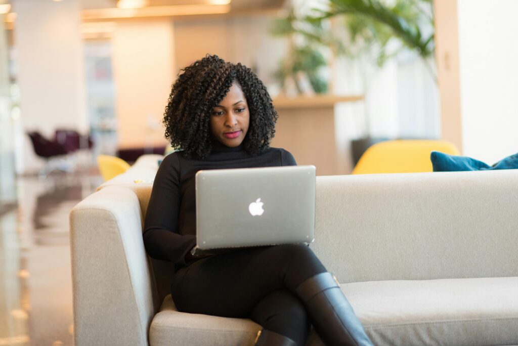 Social media manager working on a silver laptop in a modern office space with stylish furnishings and decor.