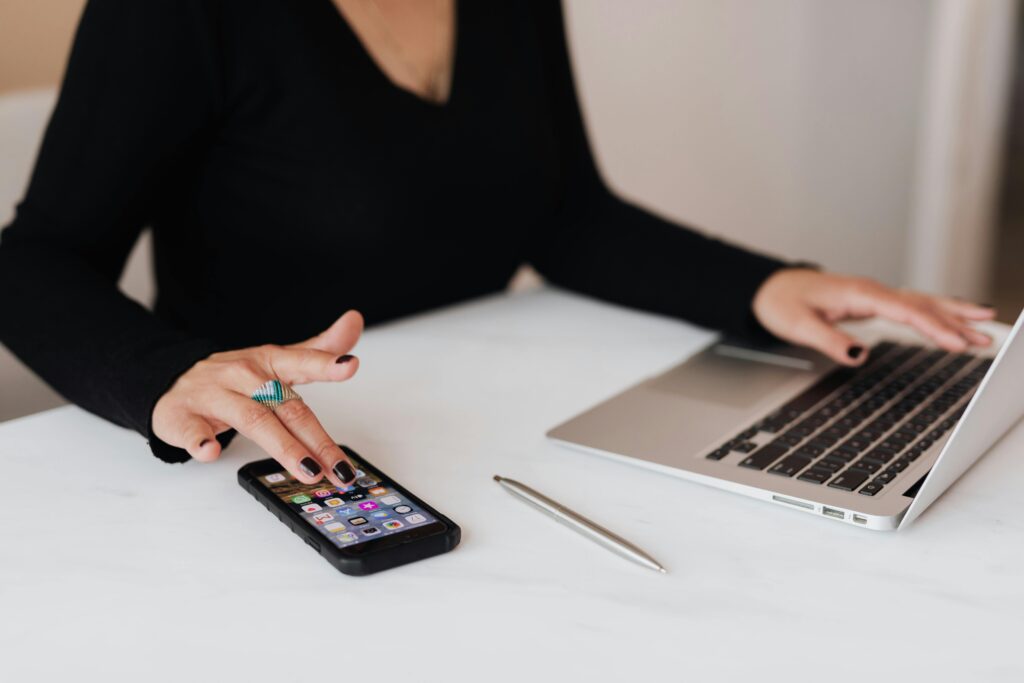 A focused individual multitasking with a smartphone and laptop, showcasing the work setup for an off-page SEO expert key skills summary.
