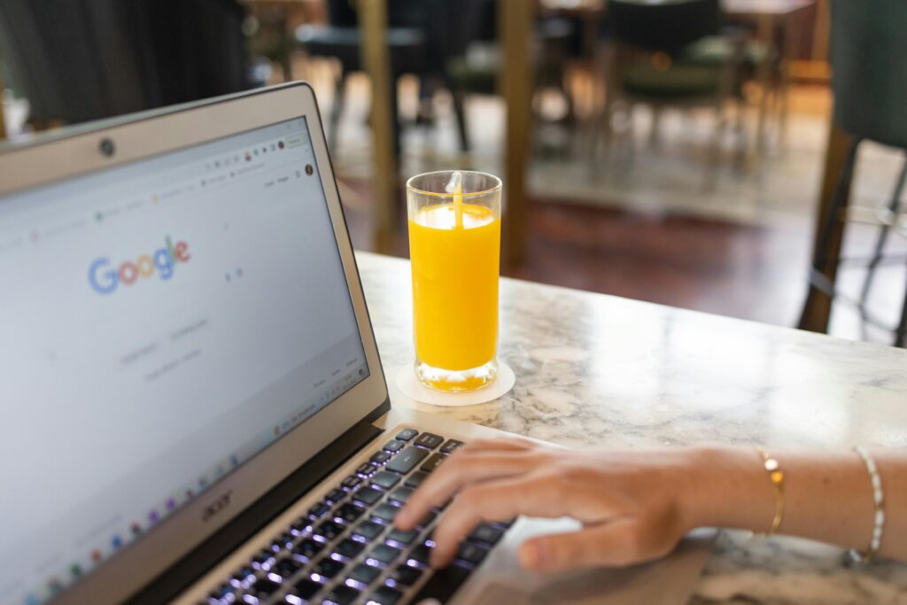 SEM director key skills summary: A marble table with a laptop displaying the Google homepage, next to a glass of orange juice.