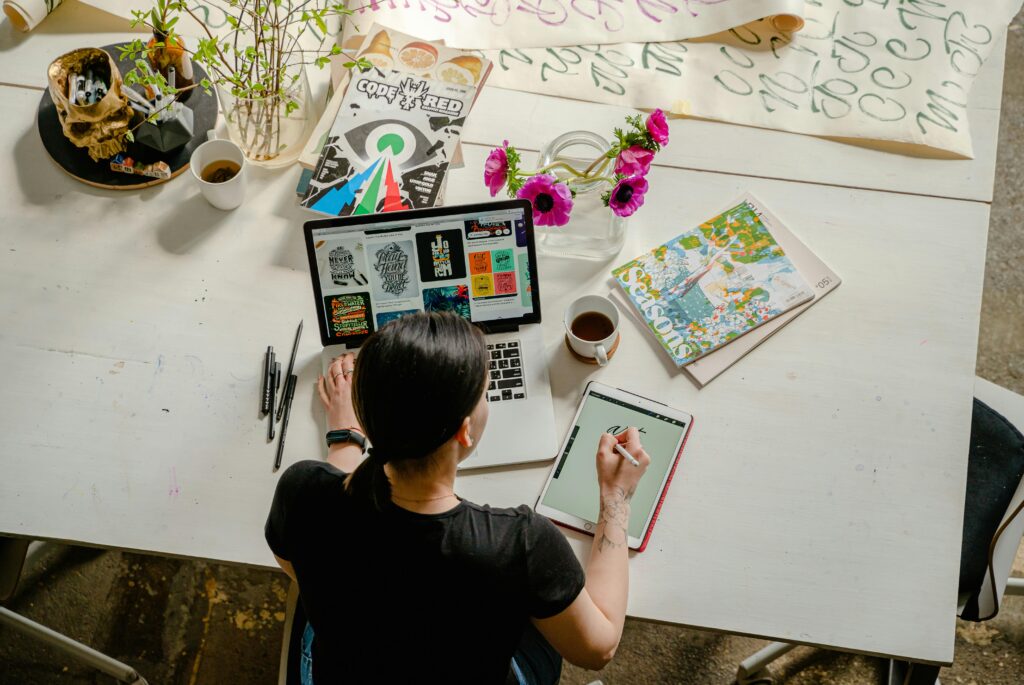 A graphic designer's workspace featuring a laptop displaying design work, a digital drawing tablet, and creative materials, highlighting a graphic designer key skills summary.