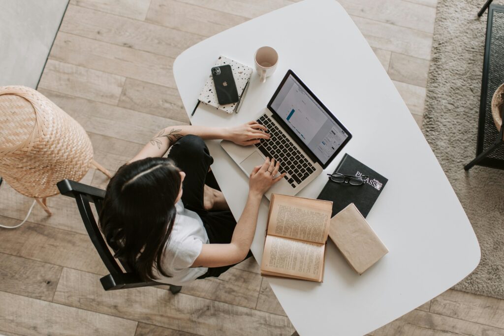 Overhead view of a laptop with a graph on its screen, surrounded by books, a notebook, a smartphone, glasses, and a coffee mug, illustrating a local SEO consultant key skills summary.